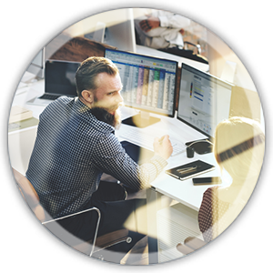 man sitting at a desk working on a computer with multiple screens